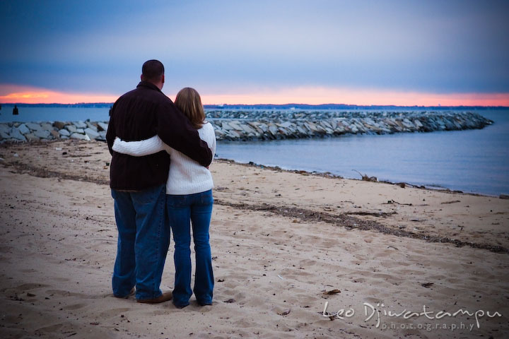 guy and girl, engaged couple, fiancee, looking at beautiful sunset color on the horizon. Engagement Photographer Matapeake Beach, Chesapeake Bay