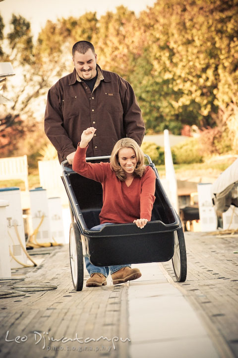 guy and girl having fun riding cart on marina pier by Hemingways and Chesapeake Bay Beach Club. Engagement Photographer Matapeake Beach, Stevensville