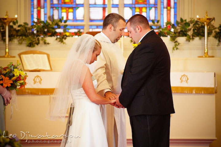 The officiant, the reverend, is giving blessing to the bride and groom. Kent Island Methodist Church KIUMC Wedding Photographer Maryland