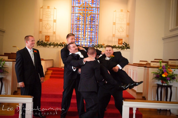 Best man and groomsman attempting to lift up groom, laughing. Kent Island Methodist Church KIUMC Wedding Photographer Maryland