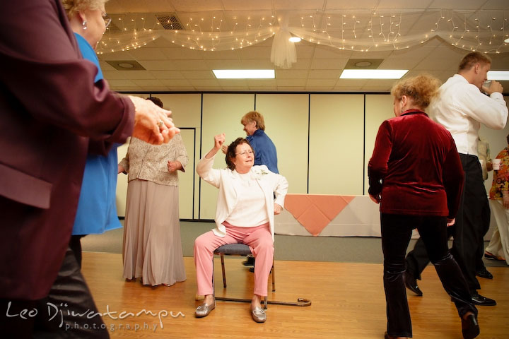 Grandmother sittin on chair, dancing with other guests. Kent Island Flowers MD American Legion Wedding Photographer