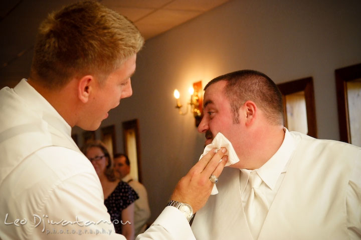 Best man help groom wipe cake icing from his face. Kent Island Flowers MD American Legion Wedding Photographer