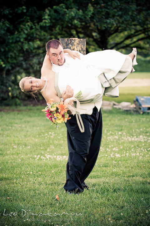 Bride holds flower bouquet. Groom lift up bride, almost upside down. Kent Island Flowers MD American Legion Wedding Photographer