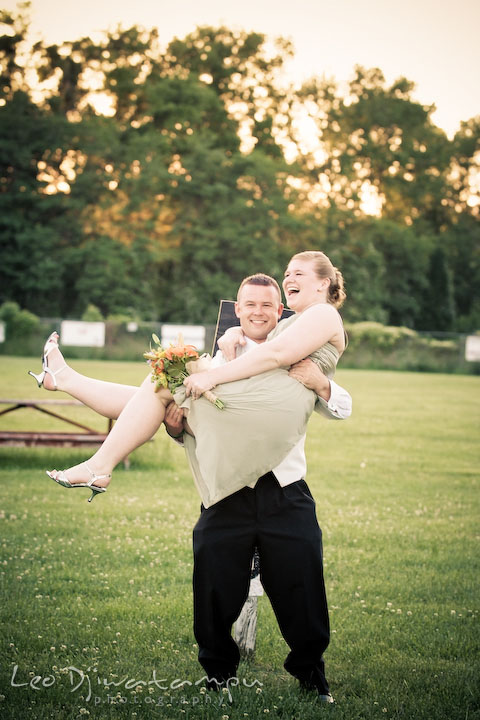 Engaged groomsman lift up his fiancee bridesmaid, laughing. Kent Island Flowers MD American Legion Wedding Photographer