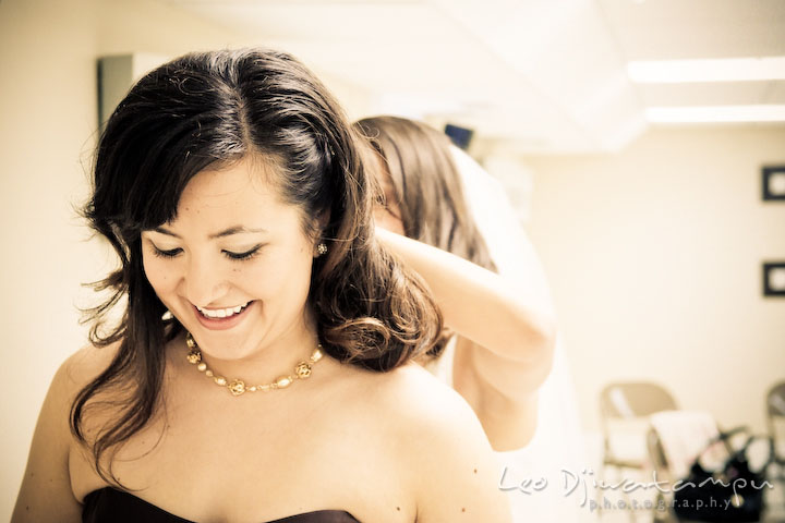Bride helps bridesmaid puting on necklace. Stafford Virginia Wedding Photographer