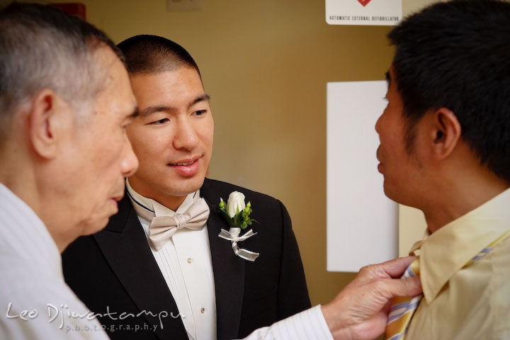 Groom and family member help putting on tie for the father of the groom. Stafford Virginia Wedding Photographer