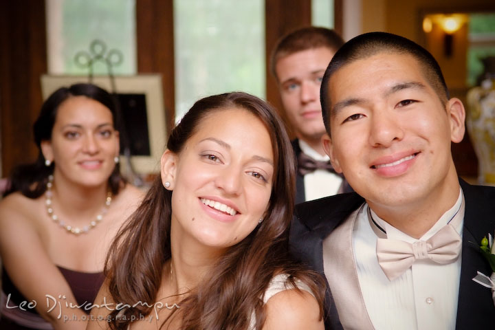 Bride and groom smiling with maid of honor and groomsman in the background. Fredericksburg Square Wedding, Fredericksburg Virginia Wedding Photographer