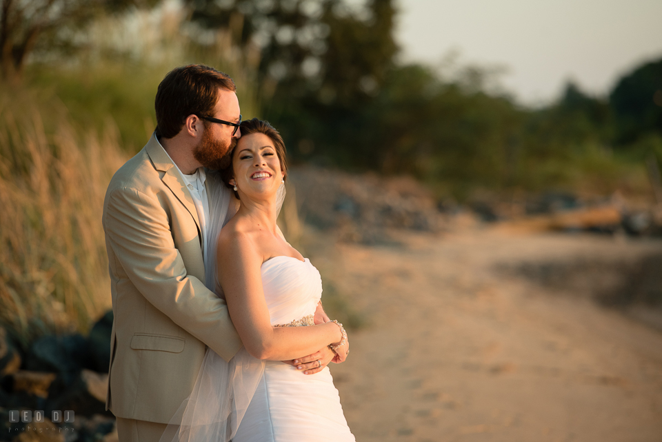 Eastern Shore Maryland Bride cuddling with Groom on the beach during sunset over the bay photo by Leo Dj Photography