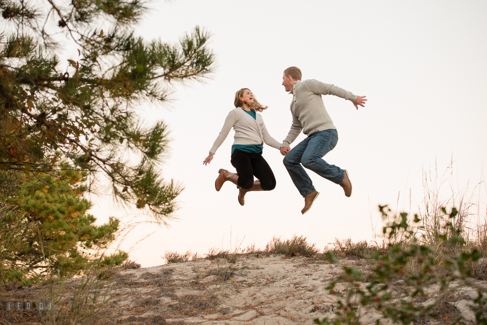 Cape Henlopen State Park Delaware engaged man jumping his fiancee for engagement photo by Leo Dj Photography.