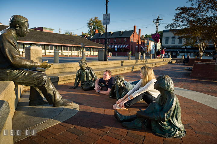 Engaged couple listening to Kunta Kinte statue. Pre-wedding engagement photo session at Annapolis city downtown harbor, Maryland, Eastern Shore, by wedding photographers of Leo Dj Photography. http://leodjphoto.com