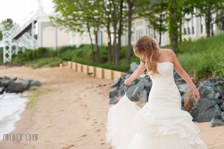 Bride on the beach adjusting her train. Kent Island Maryland Chesapeake Bay Beach Club wedding ceremony and getting ready photo, by wedding photographers of Leo Dj Photography. http://leodjphoto.com