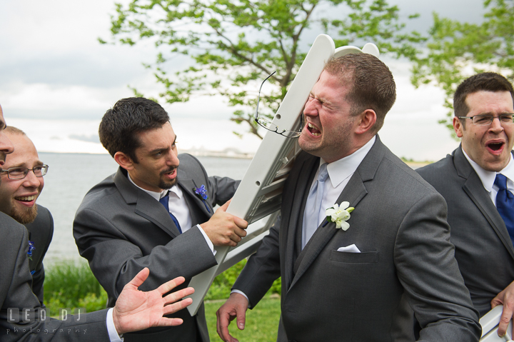 A groomsman hit Groom's head with a folding chair. Kent Island Maryland Chesapeake Bay Beach Club wedding reception party photo, by wedding photographers of Leo Dj Photography. http://leodjphoto.com