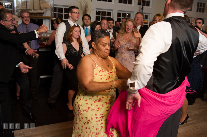 Lady guest wrap her pink scarf around Groom's butt while dancing. Kent Island Maryland Chesapeake Bay Beach Club wedding reception party photo, by wedding photographers of Leo Dj Photography. http://leodjphoto.com