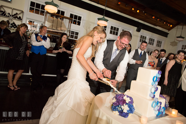 Bride and Groom laughing trying to pull piece of the cake. Kent Island Maryland Chesapeake Bay Beach Club wedding reception party photo, by wedding photographers of Leo Dj Photography. http://leodjphoto.com