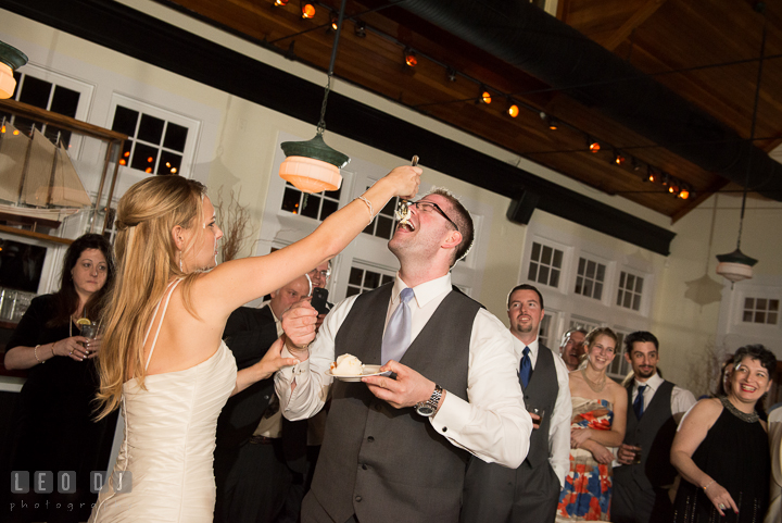 Bride aimed cake on Groom's nose while feeding him. Kent Island Maryland Chesapeake Bay Beach Club wedding reception party photo, by wedding photographers of Leo Dj Photography. http://leodjphoto.com