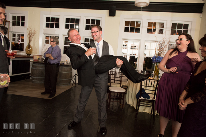 Groom picked up and carried one of the male guests. Kent Island Maryland Chesapeake Bay Beach Club wedding reception party photo, by wedding photographers of Leo Dj Photography. http://leodjphoto.com