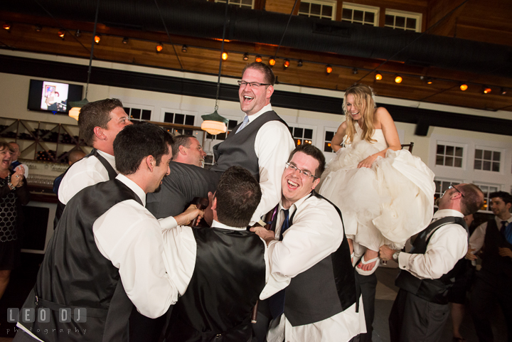 Bride and Groom laughing while being lifted up on chairs. Kent Island Maryland Chesapeake Bay Beach Club wedding reception party photo, by wedding photographers of Leo Dj Photography. http://leodjphoto.com