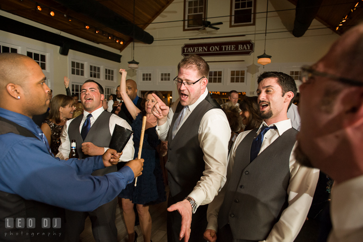 Groom and guests singing while Onyx Band singer plays cowbell percussion. Kent Island Maryland Chesapeake Bay Beach Club wedding reception party photo, by wedding photographers of Leo Dj Photography. http://leodjphoto.com