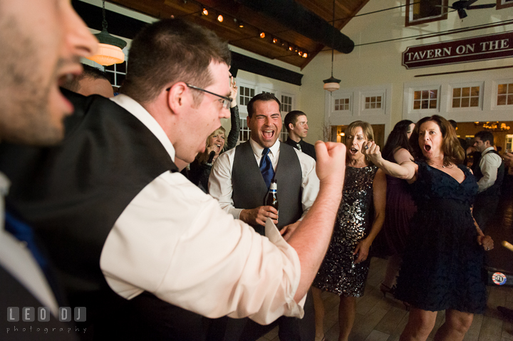 One of Groomsmen singing with another guest and making fists. Kent Island Maryland Chesapeake Bay Beach Club wedding reception party photo, by wedding photographers of Leo Dj Photography. http://leodjphoto.com