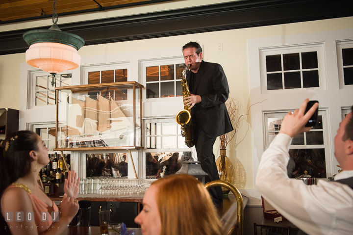 Onyx Band band member standing on top of bar and playing saxophone. Kent Island Maryland Chesapeake Bay Beach Club wedding reception party photo, by wedding photographers of Leo Dj Photography. http://leodjphoto.com