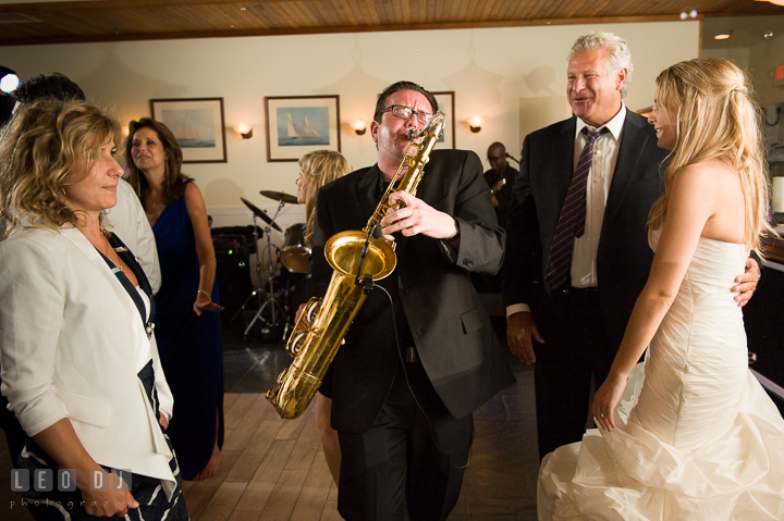 Bride and guests watching Onyx Band's saxophonist perform. Kent Island Maryland Chesapeake Bay Beach Club wedding reception party photo, by wedding photographers of Leo Dj Photography. http://leodjphoto.com