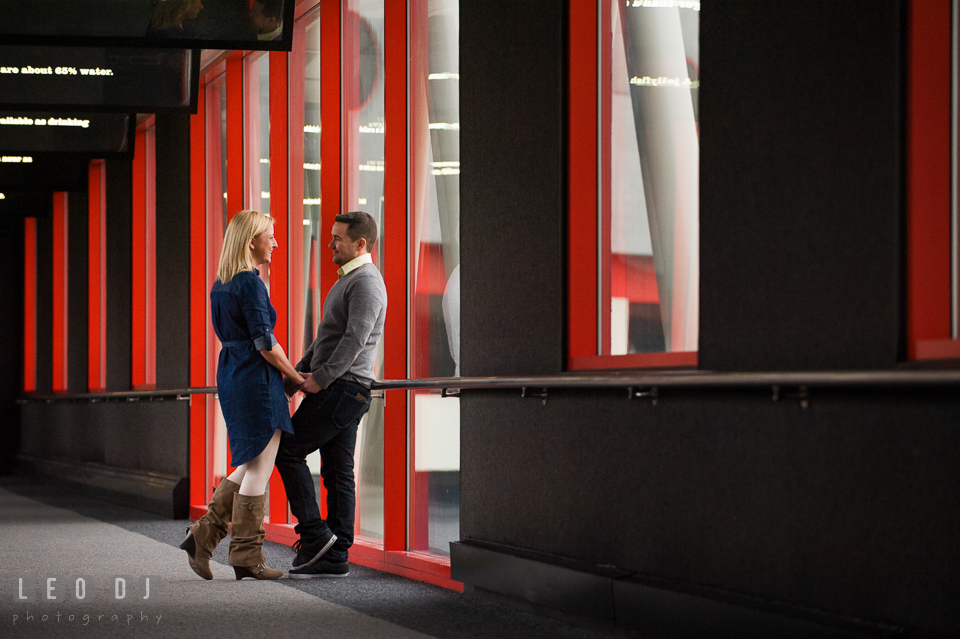 Engaged man talking and holding hands with his fiancée. Baltimore MD pre-wedding engagement photo session at National Aquarium in Baltimore, by wedding photographers of Leo Dj Photography. http://leodjphoto.com