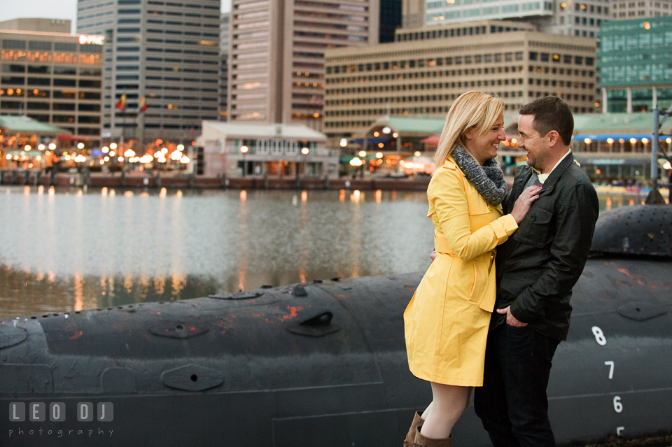 Engaged girl in yellow jacket cuddling and laughing with her fiancé. Baltimore MD pre-wedding engagement photo session at National Aquarium in Baltimore, by wedding photographers of Leo Dj Photography. http://leodjphoto.com