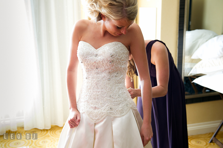 Matron of Honor buttoning up Bride's dress. Getting ready wedding photos at Baltimore Marriott Waterfront by photographers of Leo Dj Photography. http://leodjphoto.com