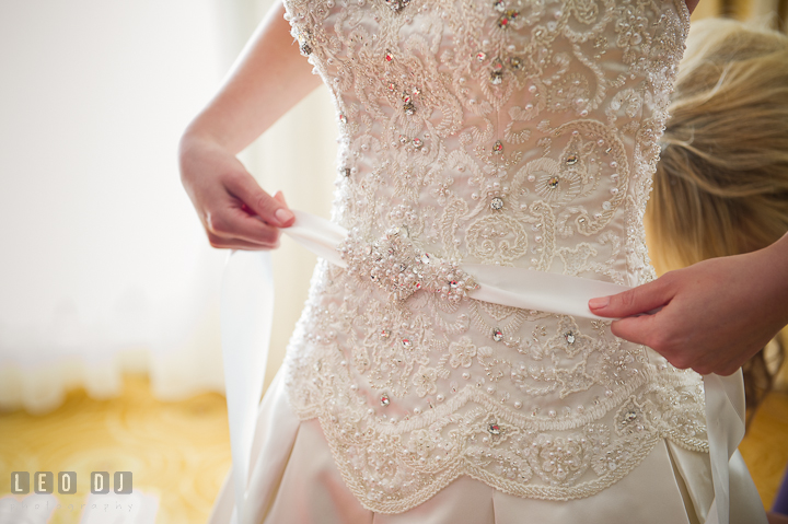 Bride putting on wedding gown belt. Getting ready wedding photos at Baltimore Marriott Waterfront by photographers of Leo Dj Photography. http://leodjphoto.com