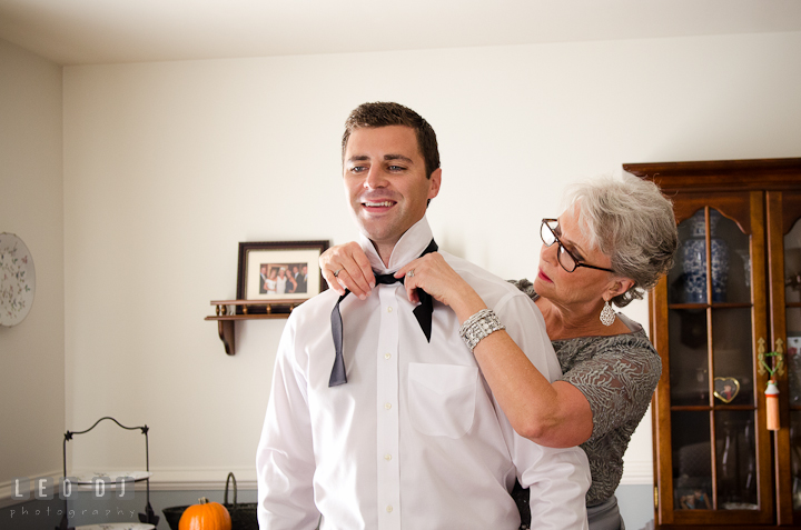 Mother of Groom help son put on bow tie. Getting ready wedding photos at Baltimore Marriott Waterfront by photographers of Leo Dj Photography. http://leodjphoto.com