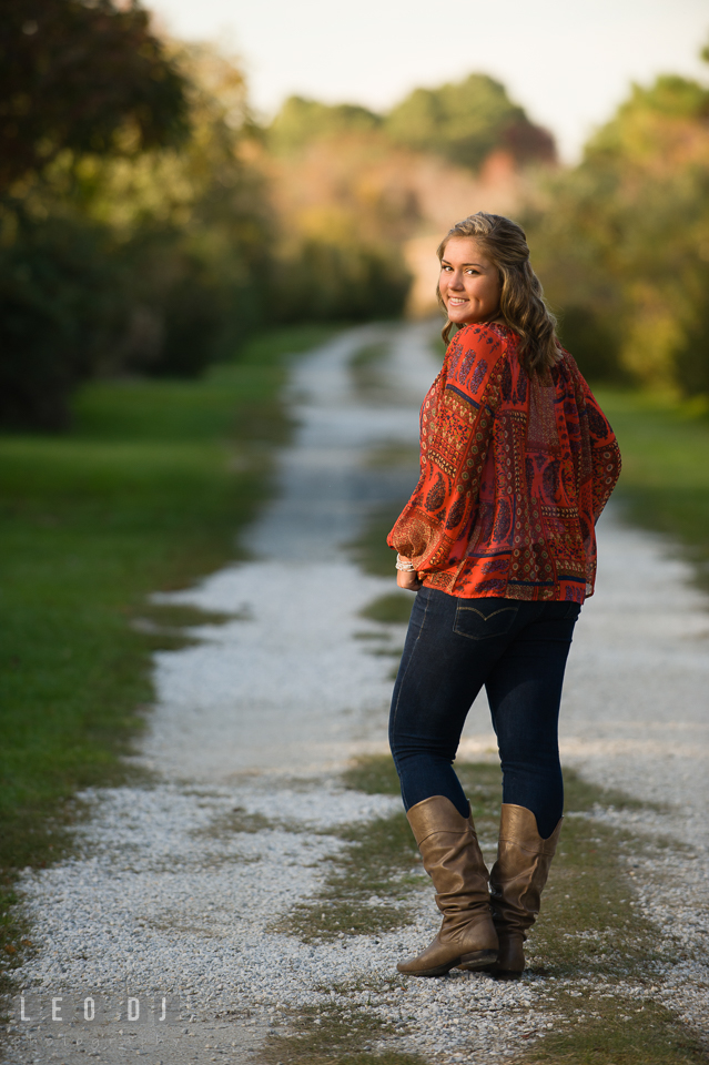 Girl in red blouse and jeans walking in a pathway. Eastern Shore, Maryland, Queen Anne's County High School senior portrait session by photographer Leo Dj Photography. http://leodjphoto.com