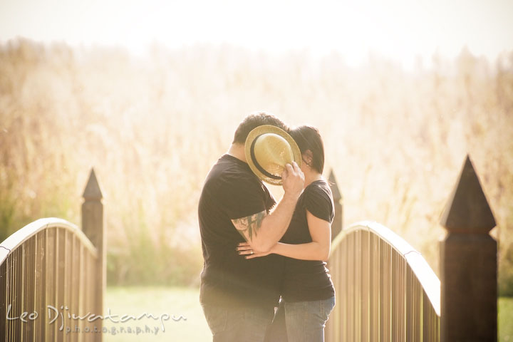 Engaged couple kissing, but covered by hat. Eastern Shore MD engagement pre-wedding photo session pier boat tattoo