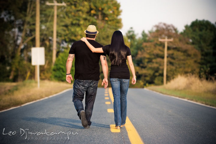 Engaged guy and girl walking together down the road. Eastern Shore MD engagement pre-wedding photo session pier boat tattoo