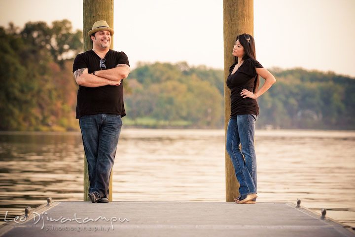 Engaged guy and girl posing by huge poles at pier. Eastern Shore MD engagement pre-wedding photo session pier boat tattoo