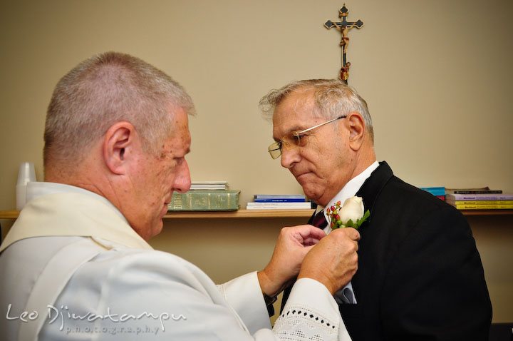A priest help putting boutonniere on father of the groom. Baywood Clubhouse at Baywood Greens Wedding, St. Christophers Church Wedding, Kent Island, Eastern Shore Maryland