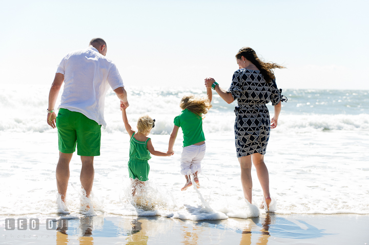 Family holding hands and jumping over the water waves on the beach. Ocean City, Maryland Eastern Shore candid children and family lifestyle photo session by photographers of Leo Dj Photography. http://leodjphoto.com