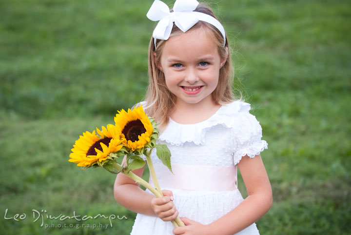 Girl holding sunflowers. Edgewater, Annapolis, Eastern Shore Maryland fun and candid children and family lifestyle photo session by photographers of Leo Dj Photography.