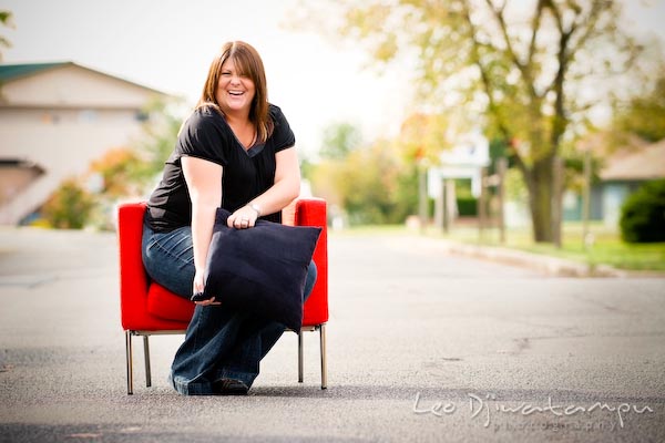 Girl on red chair posing with black pillow, laughing. Commercial work photography Annapolis Eastern Shore MD Washington DC