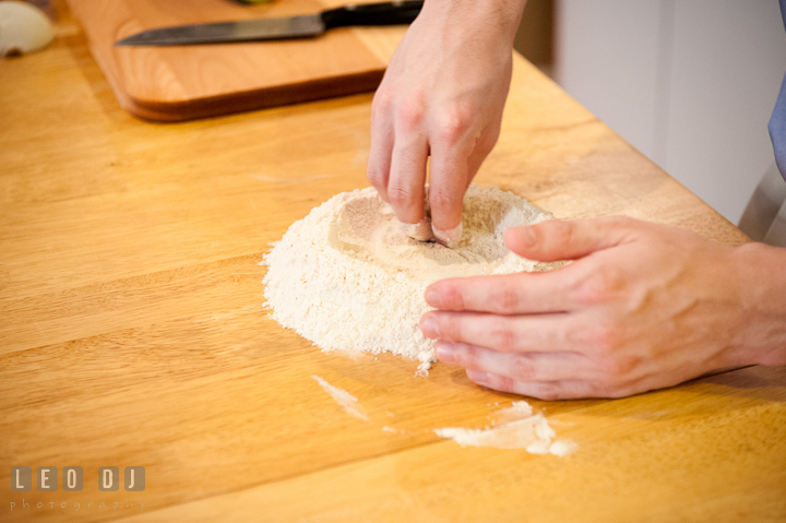 Engaged guy preparing wheat flour for pasta dough. Engagement photo session at town home near Federal Hill Baltimore Maryland by wedding photographers of Leo Dj Photography (http://leodjphoto.com)