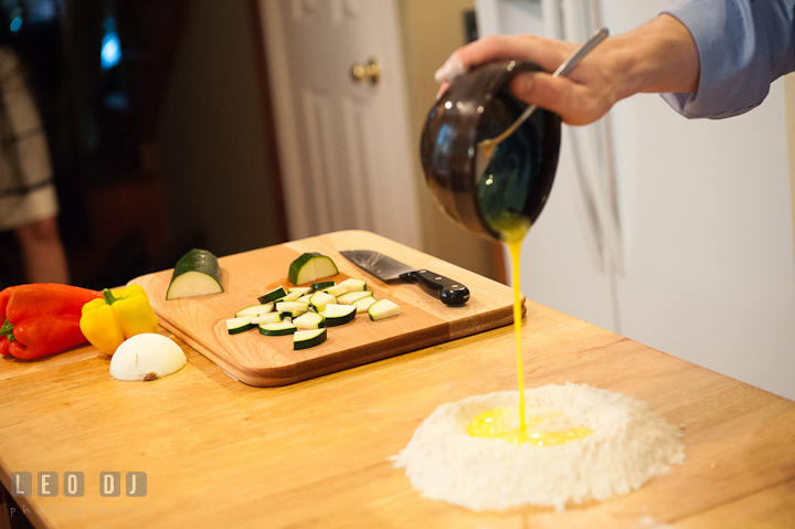 Engaged guy poured egg mixture onto flour. Engagement photo session at town home near Federal Hill Baltimore Maryland by wedding photographers of Leo Dj Photography (http://leodjphoto.com)