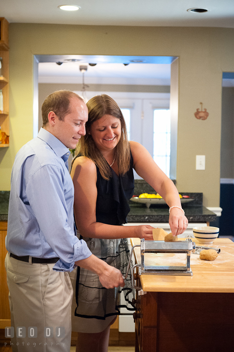 Engaged couple cooking put pasta dough in roller. Engagement photo session at town home near Federal Hill Baltimore Maryland by wedding photographers of Leo Dj Photography (http://leodjphoto.com)