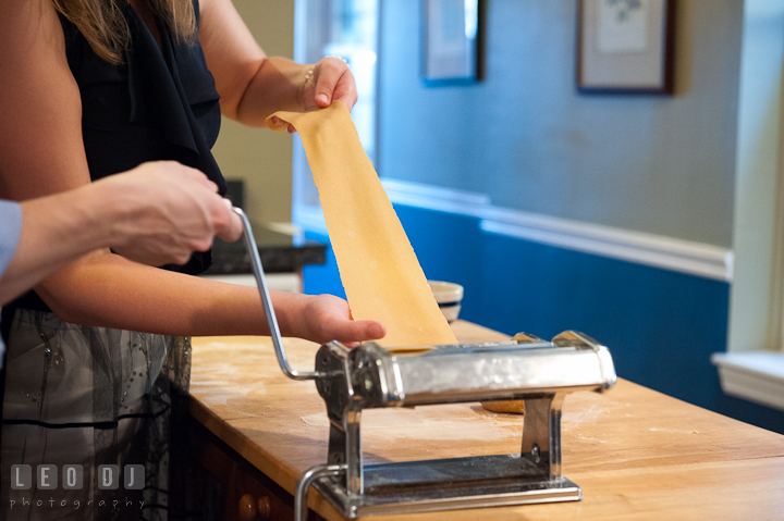 Engaged couple flatten pasta dough with a roller. Engagement photo session at town home near Federal Hill Baltimore Maryland by wedding photographers of Leo Dj Photography (http://leodjphoto.com)