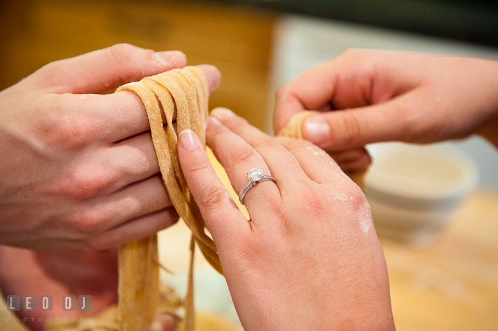 Engaged couple holding linguine, showing beautiful engagement ring. Engagement photo session at town home near Federal Hill Baltimore Maryland by wedding photographers of Leo Dj Photography (http://leodjphoto.com)