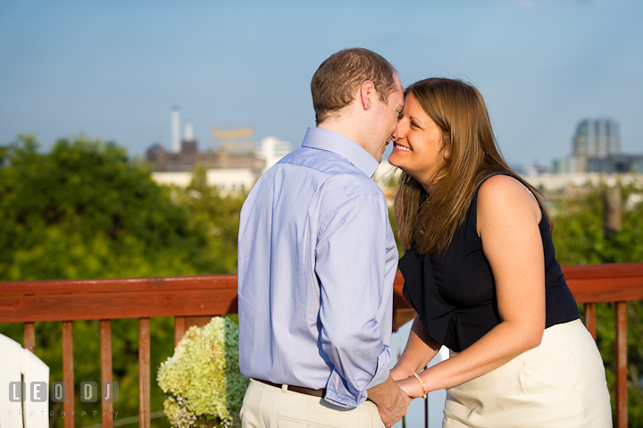 Engaged couple holding hands and touching noses on their rooftop deck. Engagement photo session at town home near Federal Hill Baltimore Maryland by wedding photographers of Leo Dj Photography (http://leodjphoto.com)