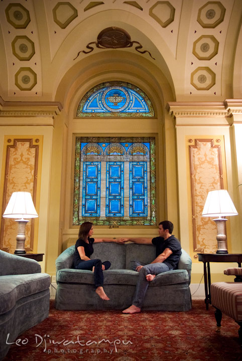 Engaged guy sitting on a sofa holding his fiancée's hand. Tremont Plaza Hotel and Grand Historic Venue Baltimore Pre-wedding Engagement Photo Session by wedding photographers Leo Dj Photography