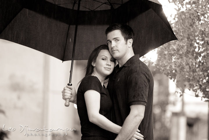 Engaged couple cuddling under the rain and umbrella. Tremont Plaza Hotel and Grand Historic Venue Baltimore Pre-wedding Engagement Photo Session by wedding photographers Leo Dj Photography