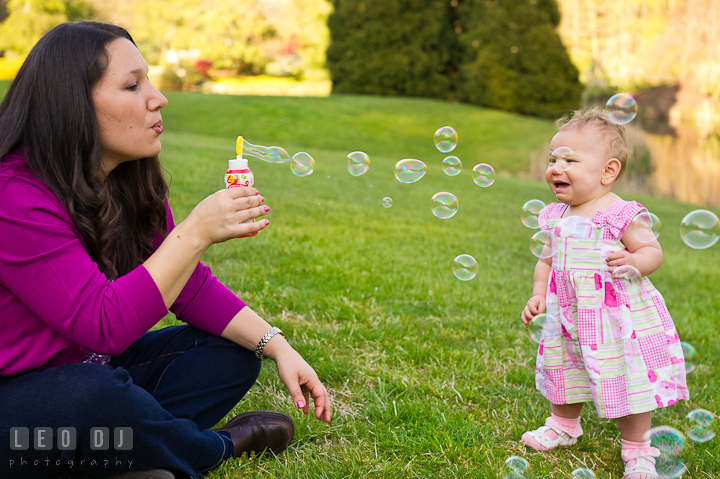 Mother blowing bubbles, baby crying. Washington DC, Silver Spring, Maryland candid children and family lifestyle photo session by photographers of Leo Dj Photography.