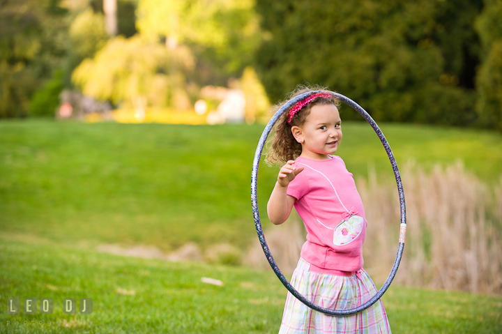 Cute girl putting hula hoop on her head. Washington DC, Silver Spring, Maryland candid children and family lifestyle photo session by photographers of Leo Dj Photography.