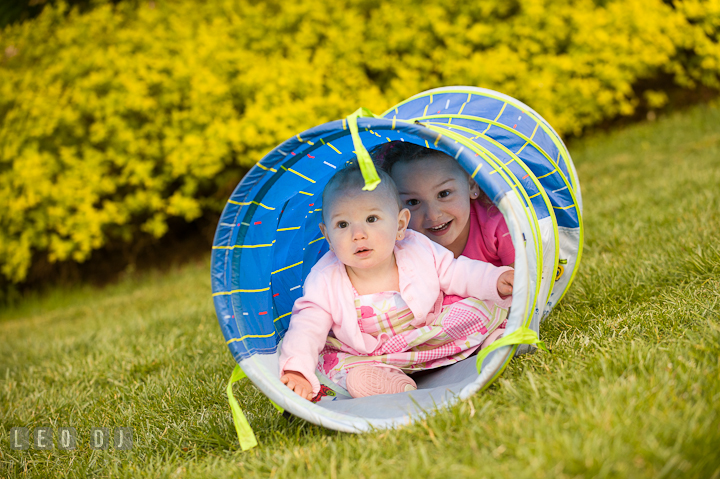 Baby girl and her sister crawling through tube. Washington DC, Silver Spring, Maryland candid children and family lifestyle photo session by photographers of Leo Dj Photography.