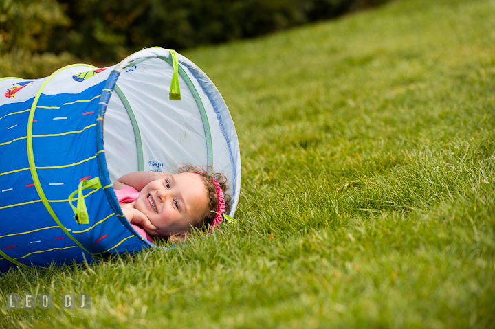 Cute little girl laying inside tube laughing. Washington DC, Silver Spring, Maryland candid children and family lifestyle photo session by photographers of Leo Dj Photography.